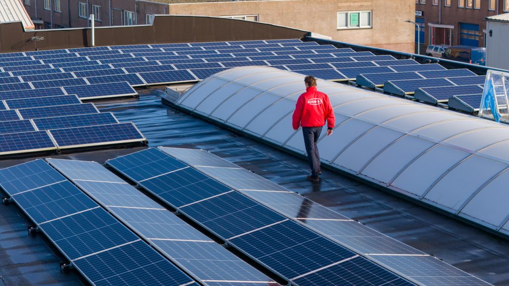 Medewerker van Rood B.V. loopt langs zonnepanelen op een bedrijfsdak