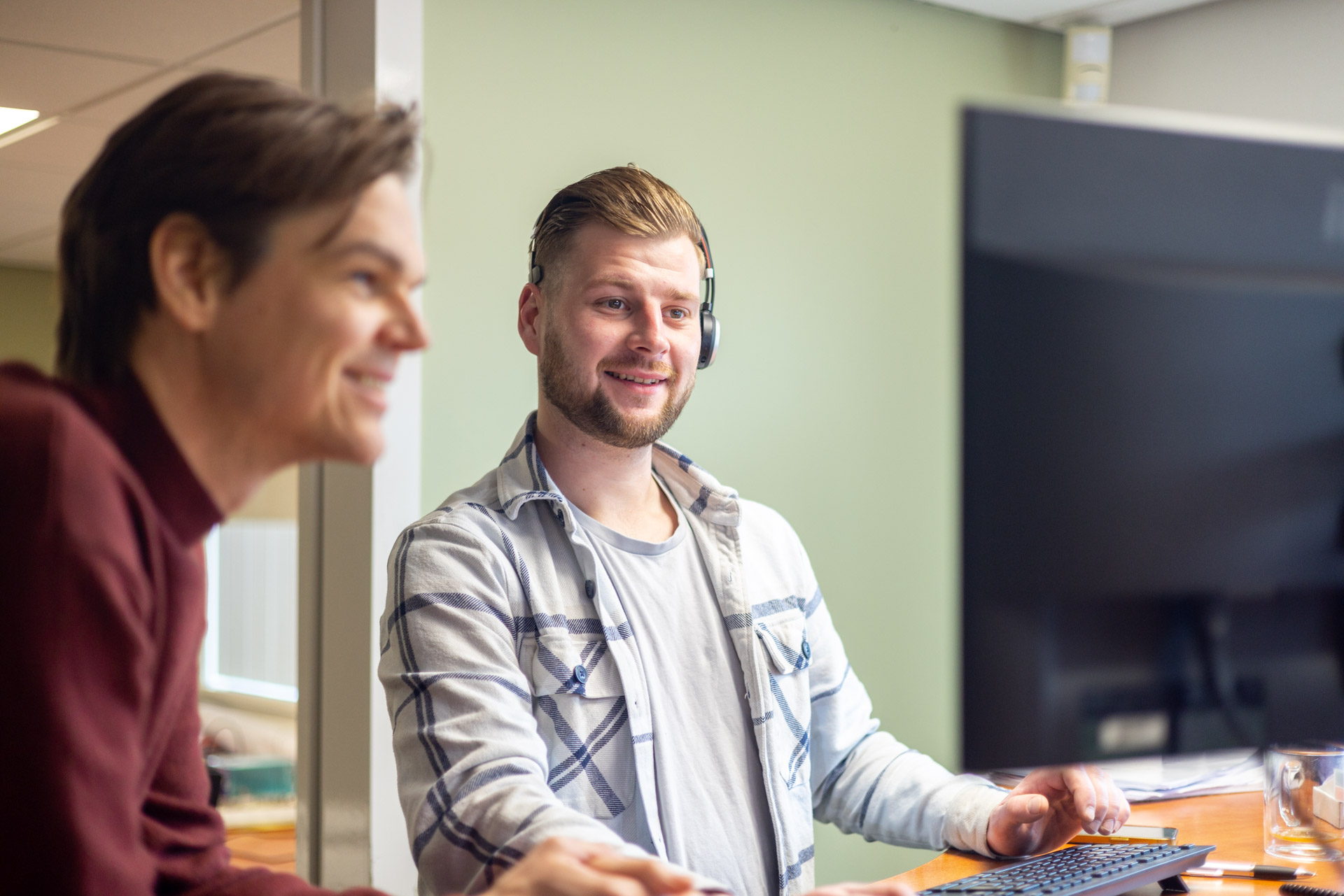 Medewerker met headset en collega overleggen over projectplanning